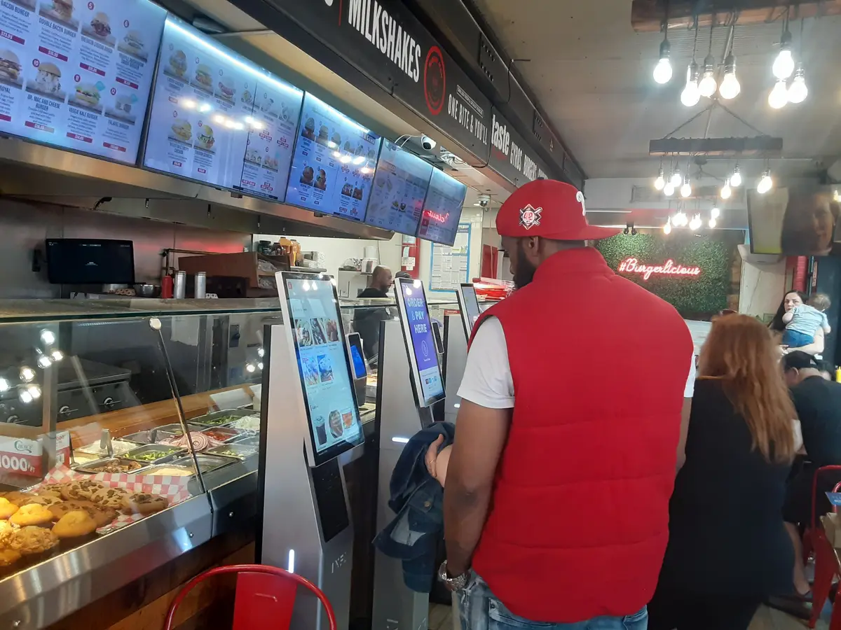 Guests ordering at INFI kiosks in a Times Square burger shop